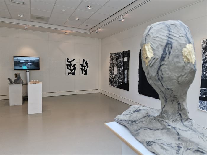 Overzicht van de expositieruimte met een beeld op de voorgrond