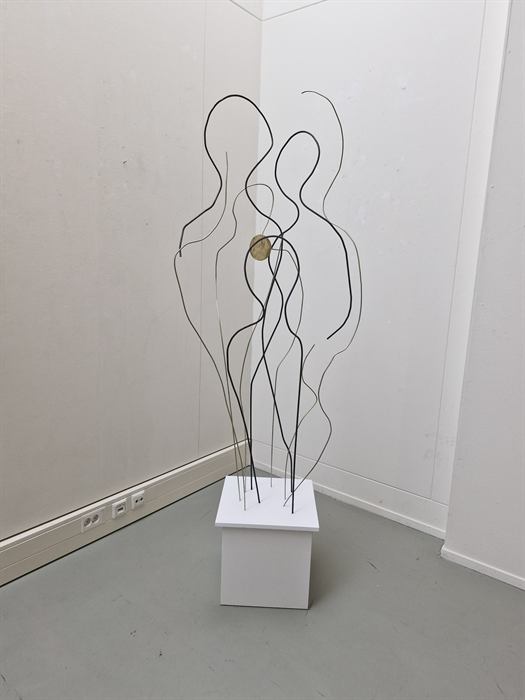 Draadsculptuur van twee figuren op een witte sokkel
